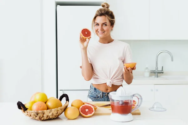 Jonge Vrolijke Vrouw Met Rijpe Grapefruits Die Thuis Vers Sap — Stockfoto