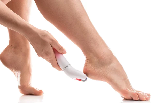 Closeup of Female feet and electric foot file for callus and dead skin removal on white background