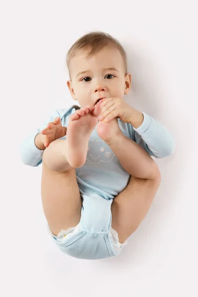 Чарівний Маленький Хлопчик Романі Лежить Кладе Ногу Рот Білому Тлі — стокове фото
