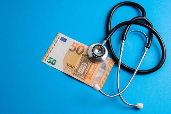 一个50欧元钞票和一个蓝色背景听诊器的闭塞镜头 保健和社区医药价格的概念 — 图库照片