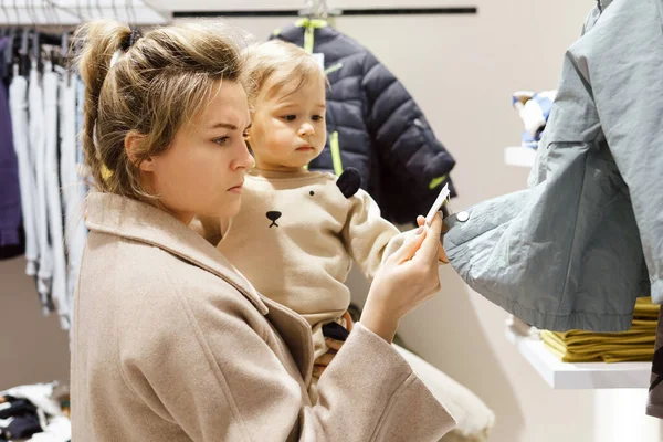 Young Woman Her Baby Son Choosing Clothing Clothes Store — Stock Photo, Image