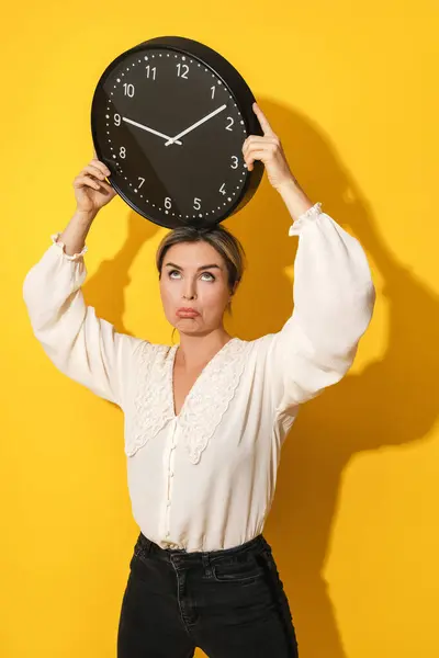 Mujer Joven Trastornada Sosteniendo Reloj Grande Sobre Fondo Amarillo — Foto de Stock