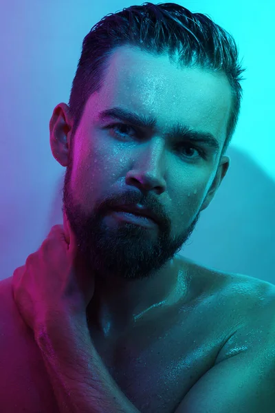 Portrait of handsome young man with wet skin in neon light