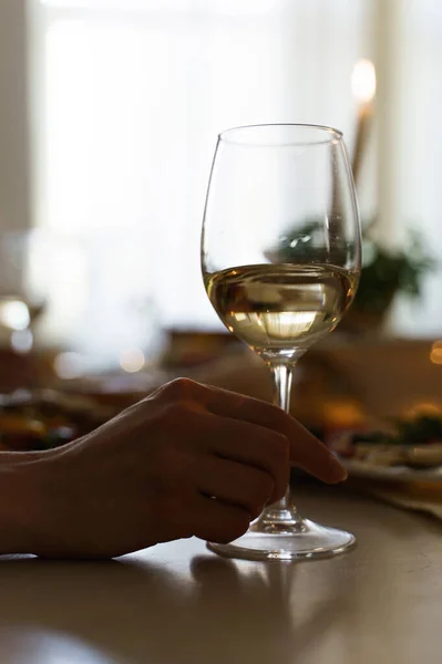 テーブルで白ワインのグラスを持っている女性のクローズアップショット — ストック写真