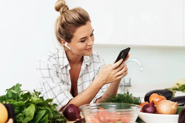 Young Pretty Woman Wireless Earbuds Using Smartphone Cooking Modern White — Stock Photo, Image