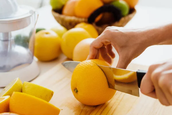 stock image Closeup of female hands with knife cutting orange fruit for homemade fresh juice