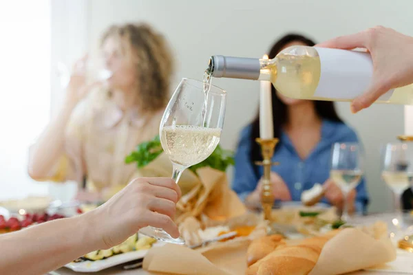 お祝いのテーブルで白ワインで彼女の友人のガラスをいっぱいに女性のクローズアップショット — ストック写真