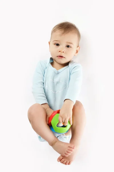 穿着保险杠的可爱的小男孩躺在床上 用白色背景的塑料玩具玩耍 — 图库照片