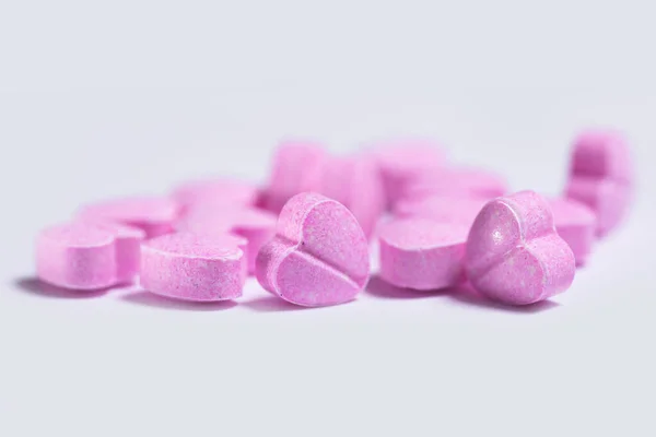 stock image Closeup shot of a pile of pink heart shaped pills on white background.