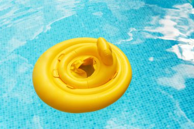 Sarı şişme bebek yüzme havuzunda yüzüyor.