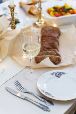 Akşam yemeği için dilimlenmiş ekmek ve mumlarla süslenmiş beyaz şarapla servis edilen şenlik masası..