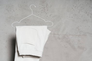 Hafif beton duvara asılı ince metalik askıda asılı beyaz eşofman altı modeli.