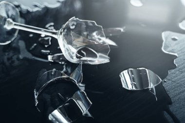 Masanın üzerinde bir sürü keskin kırıkları olan kırık şarap kadehinin yakın çekimi.