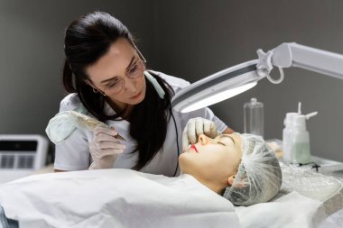 Profesyonel makyaj sanatçısı ve müşterisi dudak kızarma işlemi sırasında