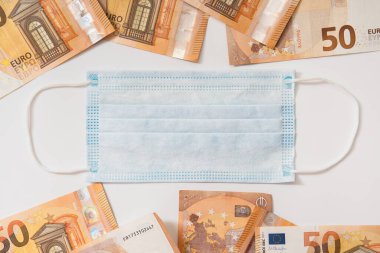 Tek kullanımlık yüz maskesi ve 50 avroluk banknotlar. Covid-19 'dan sonra ortaya çıkan mali kriz kavramı.