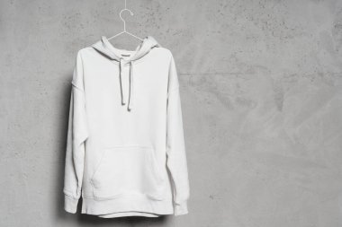İnce metalik askıda beton duvara asılı beyaz kapüşonlu kapüşonlu bir model.