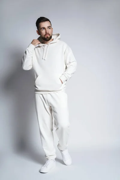 Schöner Mann Mit Weißem Kapuzenpulli Und Hose Posiert Auf Grauem — Stockfoto