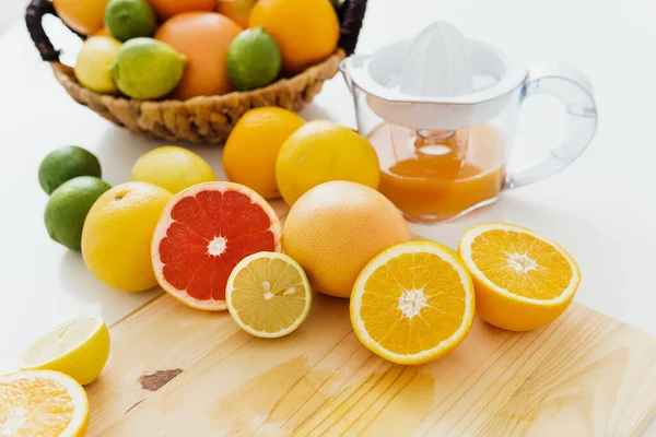 白いキッチンテーブルの上でジューサーと様々な柑橘類の閉鎖 — ストック写真