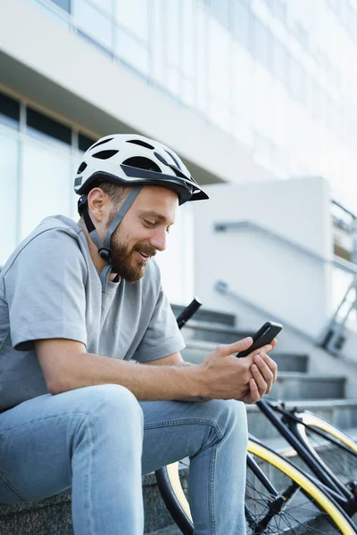 Genç Gülümseyen Sakallı Bisikletçi Merdivenlerde Bisikletiyle Oturuyor Telefonuna Bakıyor — Stok fotoğraf