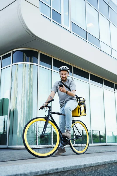 Arkasında Yalıtılmış Çantasıyla Bisiklete Binen Genç Ekspres Yemek Kuryesi Telefonuna — Stok fotoğraf