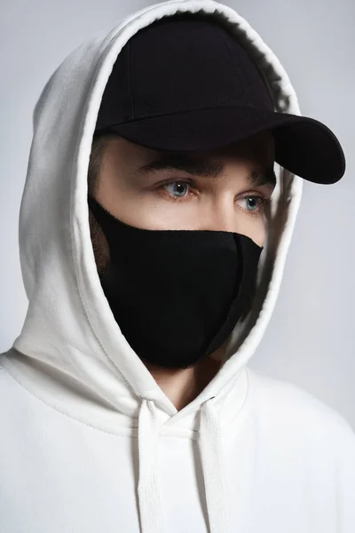 Beyaz Kapüşonlu Siyah Beysbol Şapkalı Gri Arka Planda Kumaş Maskeli — Stok fotoğraf