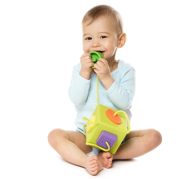 可爱的坐在保险杠里笑着的小男孩正坐在那里玩着塑料玩具 把它放在他的嘴上 放在白色的背景上 — 图库照片