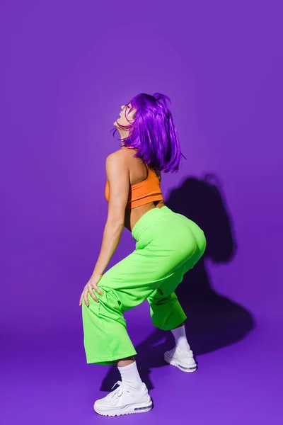 Беззаботная Танцовщица Разноцветной Спортивной Одежде Тверкает Фиолетовом Фоне — стоковое фото
