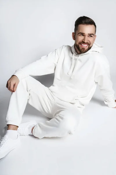 Handsome Smiling Man Wearing Blank White Hoodie Pants Sitting Light — Stock Photo, Image