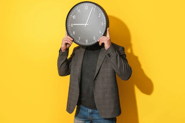 時間管理の概念 男カバー彼の顔に大きな時計で黄色の背景 — ストック写真