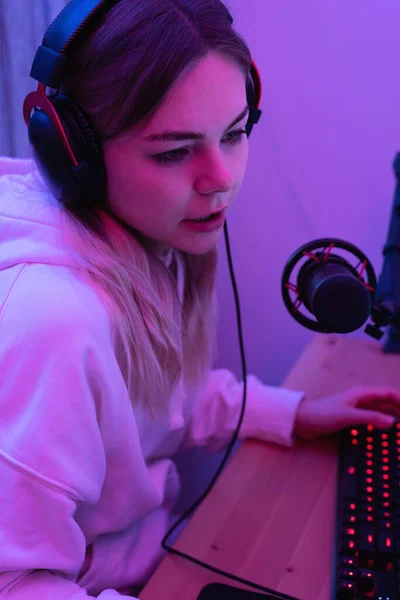 stock image Young woman blogger using condenser microphone during online podcast in room with neon light