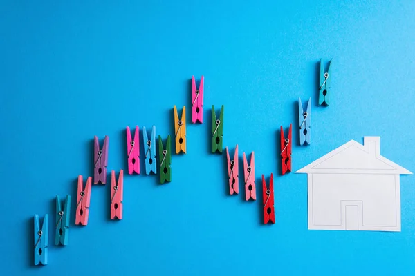 用五颜六色的木制衣针和蓝色背景的木制房子做成的财务图表的特写镜头 — 图库照片