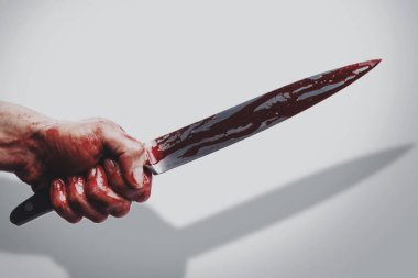 Kan lekeli bir bıçakla erkek eli beyaz arka plana gölge düşürüyor..