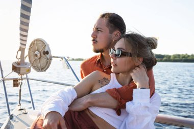 Genç ve çekici bir çift denizde yelkenli sürerken dinleniyor..