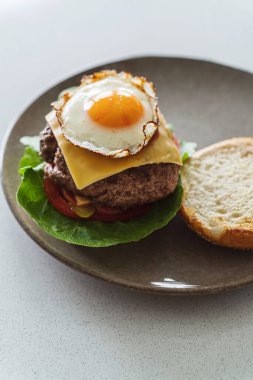 Nefis ev yapımı çizburger, mükemmel kızarmış, güneşli bir yumurta ile süslenmiş..