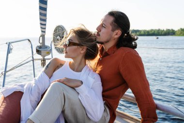 Genç ve çekici bir çift denizde yelkenli sürerken dinleniyor..