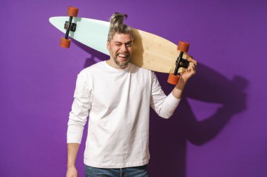 Mor arka planda beyaz kazak giyen orta yaşlı, neşeli bir adamın portresi.