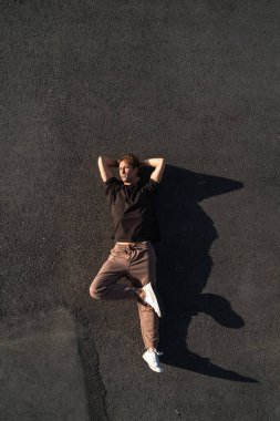 Genç ve kaygısız adamın asfaltta yatışının en üst görüntüsü