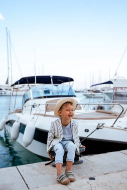 Marinadaki yatın yanındaki rıhtımda oturan şirin şık çocuk..