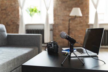 Bir gazetecinin çalışma masasına dizüstü bilgisayar, kamera, mikrofon ve defter. 