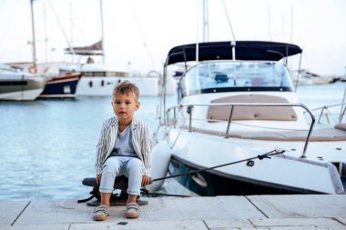 Marinadaki yatın yanındaki rıhtımda oturan şirin şık çocuk..