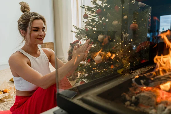 Young Woman Sits Glowing Fireplace Cozy Living Room Adorned Christmas — Stock Photo, Image