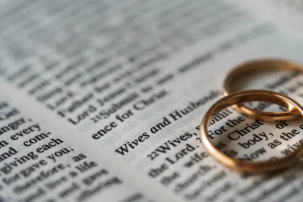 两个金光闪闪的结婚戒指和翻开的圣经代表了婚姻和两个基督徒之间的爱情 — 图库照片