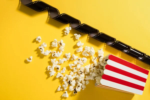 Klasik çizgili kova, lezzetli patlamış mısır ve sarı arka planda film stoku..