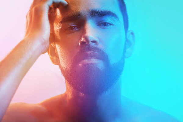 Portrait of handsome young man with wet face in blue and orange light