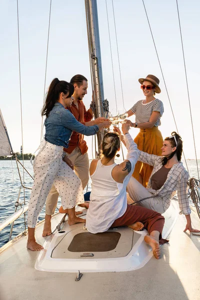 Group of happy friends drinking wine and relaxing on the sailboat during sailing in sea.