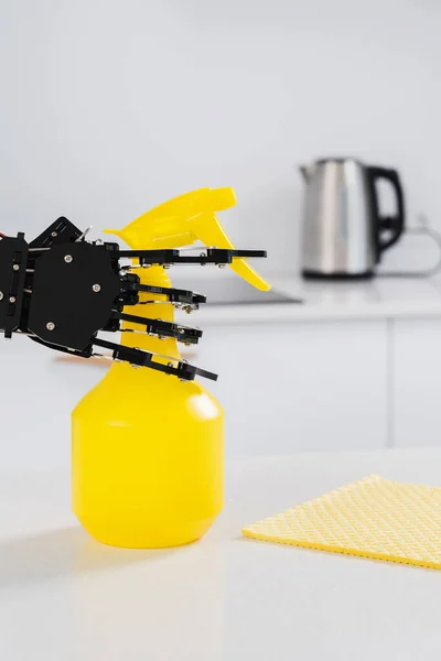 Real robot\'s hand with spray cleaner in white kitchen. Concept of  robotic process automation.