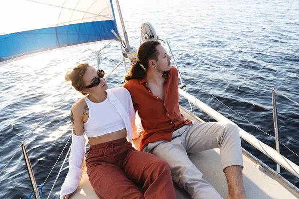 Young attractive couple relaxing on the sailboat during sailing in the sea.