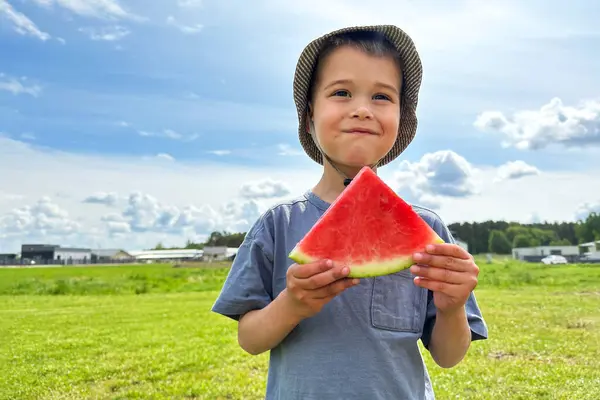 Little Boy in Bucket Hat Enjoying a Juicy Watermelon Slice on a Summer Day.