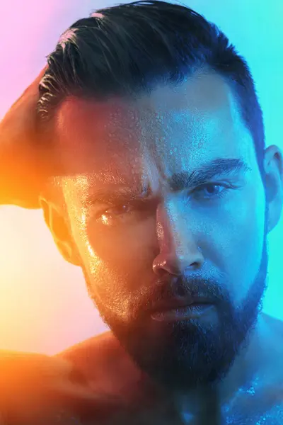 Portrait of handsome young man with wet face in blue and orange light