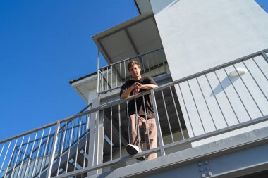 Mahallesindeki apartman kompleksinin yanında duran genç bir adamın alçak açısı.